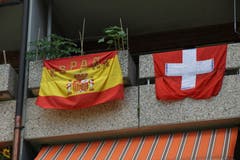 Spanisch-schweizerische Freundschaft auf einem Balkon an der Andreasstrasse in der Lachen. Dass die Schweizer Fahne das Werbeprodukt eines Bündner Bierbrauers ist, tut nichts zur Sache.