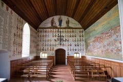 Auch über dem Eingang finden sich Namen und Wappen gefallener Habsburger. Im Bogenfeld oberhalb der Wappen die Gottesmutter Maria im Strahlenkranz mit dem Jesuskind auf dem Arm. Sie wird flankiert von Bischof Cyrill und Jakobus dem Älteren. (Bild: Boris Bürgisser, 18. Juni 2018)