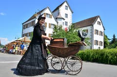 Kein Kinderwagen: die Drehorgelfrau kurbelt vor der Schlosskulisse Melodien.