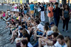 Festbesucher sitzen beim Schwanenplatz am See.
