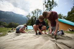 Philipp Bundi, Elias Arnold und Elias Brunner (von links) bauen ihr Zelt auf. (Bild: Jakob Ineichen, 7. Juli 2018)