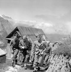 Andreas Heckmair, links, und Heinrich Harrer, Zweiter von rechts, laufen nach ihrem Aufstieg durch Grindelwald. (Bild: Keystone/ Photopress-Archiv/ Str)