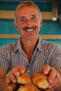 Bauernmarkt-Präsident Rolf Bischofberger vom Sunnehof bei Oberegg beigt Gipfeli auf.