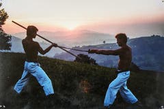 Zwei Karatemeister beim Showkampf: Peter Eigenmann mit Bo und Blacky mit Samurai-Schwert im Sonnenuntergang zwischen Wald und Heiden. (Bild: Michel Canonica/Privatarchiv Beat Cina)