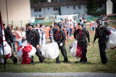Fallschirmspringer tragen ihre zusammengerafften Fallschirme. (Bild: Ralph Ribi)