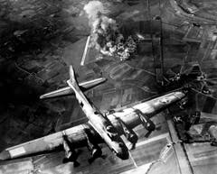 Eine B-17F beim Wegflug von einem deutschen Ziel: Da die Sichtbedingungen hervorragend sind, wurde das Flugzeugwerk neben der Flugpiste im Hintergrund von einem dicht konzentrierten Bombenhagel getroffen. (Bild: US Air Force)