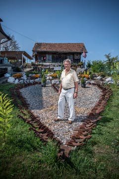 Martin Erni steht in seinem Garten inmitten eines Herzen, das aus alten Radschuhen erstellt worden ist. (Bild: Pius Amrein (21.8.2018))