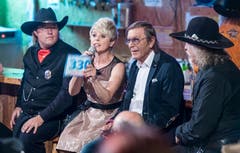 Die Moderatoren Linda Feller und Johnny Hill sitzen zwischen Cowboys.
