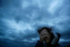 Russ Lewis schützt seine Augen vor Wind und Sand. (Bild: David Goldman/AP (Myrtle Beach, 14. September 2018))