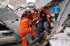 Bergung eines Opfers aus den Trümmerteilen eines zerstörten Gebäudes. (AP Photo/Tatan Syuflana)