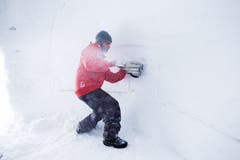 Stefan Jans schneidet beim Iglubau auf der Melchsee-Frutt erst mit der Kettensäge Blöcke, um sie danach mit der Schaufel aus der Wand zu schaufeln. (Bild: Manuela Jans (Kerns, 3. Januar 2013))