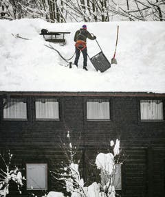 Ein Mann befreit ein Dach von der Schneelast, aufgenommen in Saalbach (Bild: APA / Keystone)