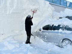 Ein Mann befreit ein schwer eingeschneites Auto von der Schneelast in Obertauern (AUT). (Bild: KEYSTONE/APA/APA/BARBARA GINDL)