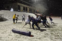 Nach der Übergabe des Footballs an den Quarterback versuchen die Defensive Linemen (dunkle Trikots) an den Spielern der Offensive Line (weisse Trikots) vorbeizukommen und den Quarterback (gelbe Jacke) zu Boden zu werfen (Sack).