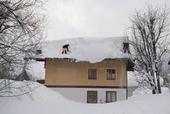 Zwei Männer schaufeln Schnee von einem Dach in Filzmoos, Österreich. (Bild: Christian Bruna / EPA)