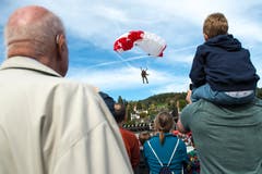 Zuschauer beobachten den Absprung der Fallschirmspringer mit anschliessender Landung in der Arena im Verkehrshaus. (Bild: Dominik Wunderli, Luzern, 12. Oktober 2019)