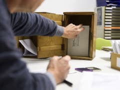 Nach Schliessung des Wahllokals holt ein Wahlhelfer die Stimmcouverts aus der Urne. (Bild: KEYSTONE/ANTHONY ANEX)