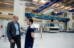 Fabrikationschef Roman Emmenegger (li) und Mirko Camerino vor dem Roboter. (Bild: Corinne Glanzmann, Buochs, 1. Oktober 2019)
