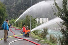 Feuerwehrmann Michael Stadler erklärt einem Mädchen, wie das Strahlrohr zu bedienen ist. (Bild: Paul Gwerder, Erstfeld, 5. Oktober 2019)