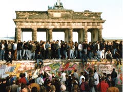 Am Tag nach der Öffnung am 9. Nov. 1989 steigen Menschen am 10. Nov. 1989 auf die Berliner Mauer vor dem Brandenburger Tor in Berlin. (Bild: KEYSTONE/AP/STR)