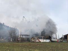 Die Feuerwehr verhindert mit ihrem Löscheinsatz das Übergreifen des Feuers auf umliegende Gebäude. (Bild: Dominik Wunderli)
