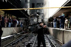 Nach dem Unglück und dem Brand der Lok versammeln sich Schaulustige auf den Perrons. Bild: Nariman El-Mofty/AP (Kairo, 27. Februar 2019)