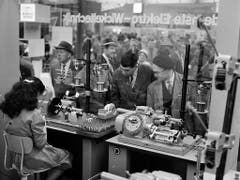 Besucher und eine Arbeiterin in der Maschinenhalle an der Mustermesse im Jahr 1960. (Bild: KEYSTONE/STR)