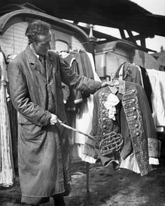 Ein Mitarbeiter des Zirkus Knie klopft im Winterquartier in Rapperswil den Staub aus einer reich verzierten Uniform, undatierte Aufnahme. (Bild: Keystone /Str)