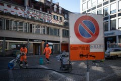 Auf der Pflästerung des Blumenmarktes werden die Bodenmarkierungen mit Hitze und einer Art grossem Staubsauger bearbeitet.