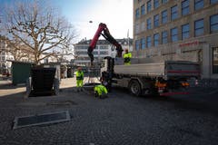 Mitarbeiter von Stadtgrün St.Gallen platzieren auf dem Markptlatz neue Pflanzkübel. Unter anderem auch in der Lücke zwischen den grünen Markthäuschen des ständigen Marktes.