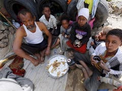 Jemenitische Bürgerkriegsopfer teilen sich eine Mahlzeit im behelfsmässigen Unterstand. (Bild: KEYSTONE/EPA/YAHYA ARHAB)