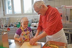 Der Küchenchef Erich Bollhalder zeigt den Schülerinnen und Schülern geduldig, was nacheinander zu erledigen ist.