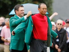 Vorjahressieger Patrick Reed kleidet Tiger Woods in das berühmte Grüne Jackett ein (Bild: KEYSTONE/EPA/ERIK S. LESSER)