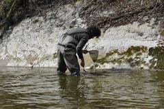 Roman Gerber schabt mit einer Abwaschbürste Material von der Felswand.
