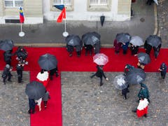 Mit Schirmen auf dem Roten Teppich: Das Erbprinzenpaar, die Schweizer Landesregierung, Weibel und andere Offizielle beim Staatsempfang. (Bild: KEYSTONE/PETER KLAUNZER)