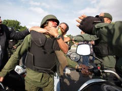 Demonstranten nehmen ausserhalb des Luftwaffenstützpunktes La Carlota bei Caracas einen Maduro-treuen Nationalgardisten in den Schwitzkasten. (Bild: KEYSTONE/AP/BORIS VERGARA)
