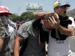 Ein verletzter Demonstrant während gewalttätigen Zusammenstössen mit der Maduro-treuen Armee in Caracas. (Bild: KEYSTONE/AP/BORIS VERGARA)