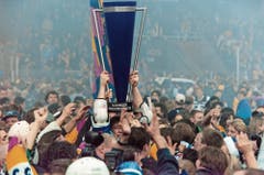 Vor fast genau 21 Jahren: Umringt von Fans stemmt Zug-Stürmer Stefan Grogg den Meisterpokal in die Höhe. (Bild: Arno Balzarini/Keystone, Davos, 11. April 1998)