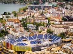Das Stahlgerüst der Arena wird mit bunten Tüchern umhüllt. (Bild: Keystone/VALENTIN FLAURAUD)