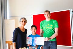 Levin Münger (mitte) nimmt die Urkunde mit der Goldmünze entgegen. Die Lehrerin Arlette von Groddeck und Dima Nikolenkov vom Verein Känguru Schweiz gratulieren dem 10-Jährigen. (Bilder: Dinah Hauser)