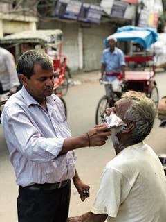 Ein Barbier am Strassenrand von New Delhi.