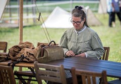 Eine Frau flickt Hosen an einem Tisch im Lager. (Bild: Reto Martin)