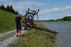Mithilfe des Traktors wird das Holz aus dem Fluss gehievt.