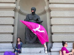 Männliche Statue mit roten Lippen und Fahne am Bundeshaus streikt mit. (Bild: KEYSTONE/PETER KLAUNZER)