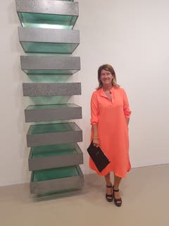 Siska Dezutter, Kunstsammlerin aus Brüssel, posiert im orangefarbenen Hemdkleid vor einer Wandinstallation von Donald Judd.
