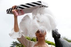 Diese Dame versucht, ihr Kunstwerk vor dem Regen zu schützen. (Bild: Photo/Alastair Grant, Ascot, 18. Juni 2019)