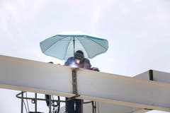 Frauenfeld TG - Ein Arbeiter schützt sich bei der Schweissarbeit mit einem Sonnenschirm gegen die heisse Sonne.