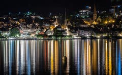 Eine Lichterspiegelung der Zuger Altstadt auf dem Zugersee. (Bild: Daniel Hegglin, Zug, 28. Juni 2019)