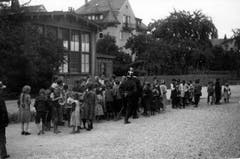 August 1914: Der Erste Weltkrieg ist erst ein paar Monate alt. Beim Restaurant Hirschen in St.Fiden stehen Frauen und Kinder für Suppe an, die von Soldaten verteilt wird. In der Bildmitte ist mit dem Rücken zur Kamera ein Kavallerist abgebildet. Zu erkennen ist er am Tschako mit weissem Pinsel und dem Säbel.
