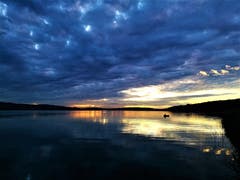 Mystische Abendstimmung beim Sonnenuntergang am Sempachersee mit einem Fischer im Boot. (Bild: Urs Gutfleisch, Sempach, 11. Juli 2019)